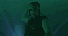 a man in a bandana holds a sword in front of a blue and red light