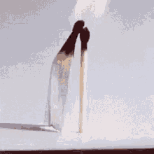 a silhouette of a person standing on a pole in front of a white wall