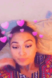 a woman laying on a bed with pink hearts on her head