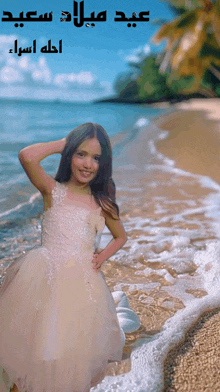 a girl in a white dress stands on a beach with arabic writing