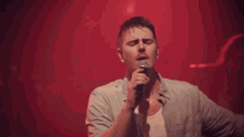 a man singing into a microphone with his hands up