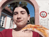a woman eating a slice of pizza in front of a sign which says 4.0m