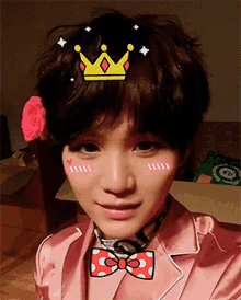 a woman wearing a pink jacket and a bow tie has a crown on her head