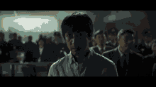 a man with glasses stands in front of a crowd