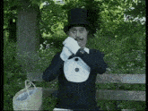 a man wearing a top hat and gloves is standing on a bench .