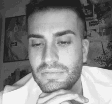 a man with a beard is crying in a black and white photo with his hands on his chin .