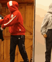 a person wearing a red hoodie that says supreme on the sleeve