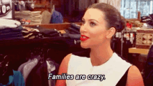 a woman with red lipstick is sitting in a clothing store and saying families are crazy .