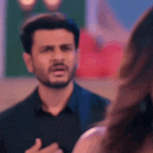 a man with a beard is talking to a woman in a room .