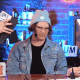 a man wearing a beanie and glasses is sitting at a table