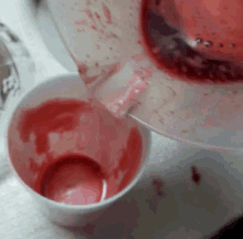 a pitcher of red liquid is being poured into a white cup