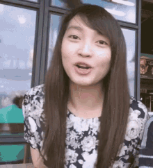 a woman with long hair is wearing a floral top