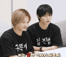 two young men wearing black shirts with chinese characters on them