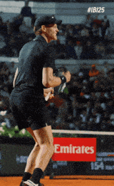 a man holding a tennis racquet on a tennis court with an emirates sign in the background