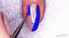 a woman is applying blue nail polish to her nails with a pair of tweezers .