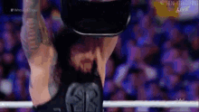 a wrestler wearing a virtual reality headset is standing in a ring .