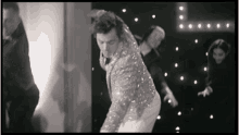 a man in a sequined suit is dancing on a stage .
