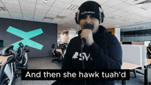 a man singing into a microphone with the words " and then she hawk tuah 'd " behind him