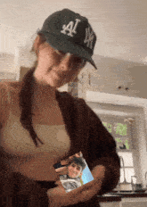 a woman wearing a ny hat holds a picture of a young man