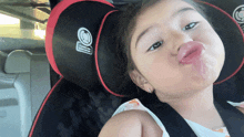 a little girl sitting in a car seat with a warning label on the back