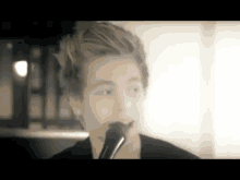 a young man is singing into a microphone in a blurry photo .