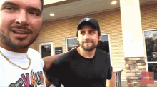 two men are posing for a picture and one is wearing a shirt that says ' vault ' on it