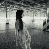 a woman in a white dress stands in a parking garage