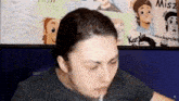 a man is sitting in front of a wall with cartoons on it and eating something .
