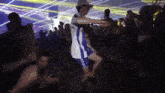 a man in a white shirt and blue shorts is dancing in a crowd of people .