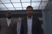 a man in a suit stands in front of a sign that says e