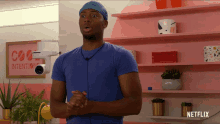 a man in a blue shirt stands in front of a pink wall with a sign that says cool intentions