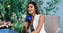 a woman is sitting on a couch holding a microphone in her hand .
