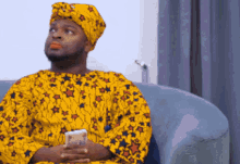 a man sitting on a couch wearing a yellow shirt with stars on it