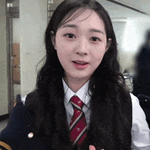 a girl in a school uniform with a tie that has the letter x on it