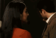a woman in a red shirt is talking to a man in a suit while a man looks on .