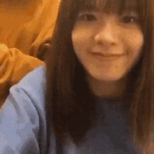 a close up of a woman 's face with long hair and a blue shirt smiling .