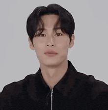 a young man wearing a black jacket and a black shirt is looking at the camera .