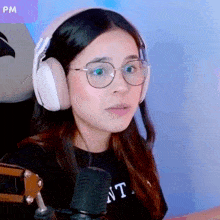 a girl wearing headphones and glasses is looking at the camera .