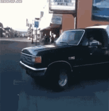 a black truck is parked in front of a building that has a sign on it that says ' cedar valley '