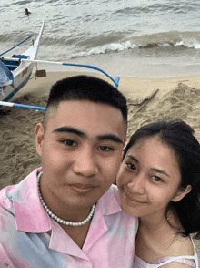 a man and a woman pose for a picture on the beach
