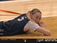 a female basketball player is laying on the floor in front of a ncaa women 's basketball championship advertisement