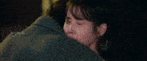 a woman is hugging a man in a grey coat