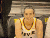 a woman wearing a fever jersey sits in a bleacher