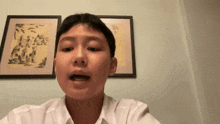 a young boy is talking in front of two framed pictures