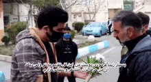 a man wearing a mask is holding a plant in his hand while talking to another man .