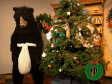 a stuffed bear standing next to a christmas tree with a wreath in the background