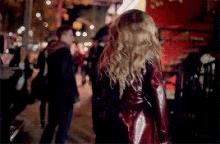 a woman in a red leather jacket is walking down a crowded street .