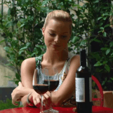 a woman sitting at a table with a glass of wine and a bottle of wine