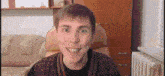a man is smiling while sitting in a chair in a living room