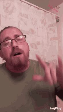 a man with glasses and a beard is standing in front of a shower curtain that says beach